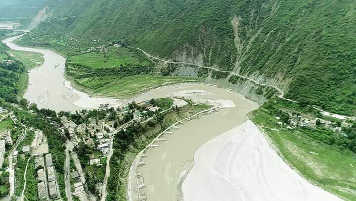 Uttarakhand landslides-"Aerial view of a river bending through a Himalayan valley in Uttarakhand, showing green terraces, scattered houses, and landslide-affected slopes, highlighting flood-prone areas."-